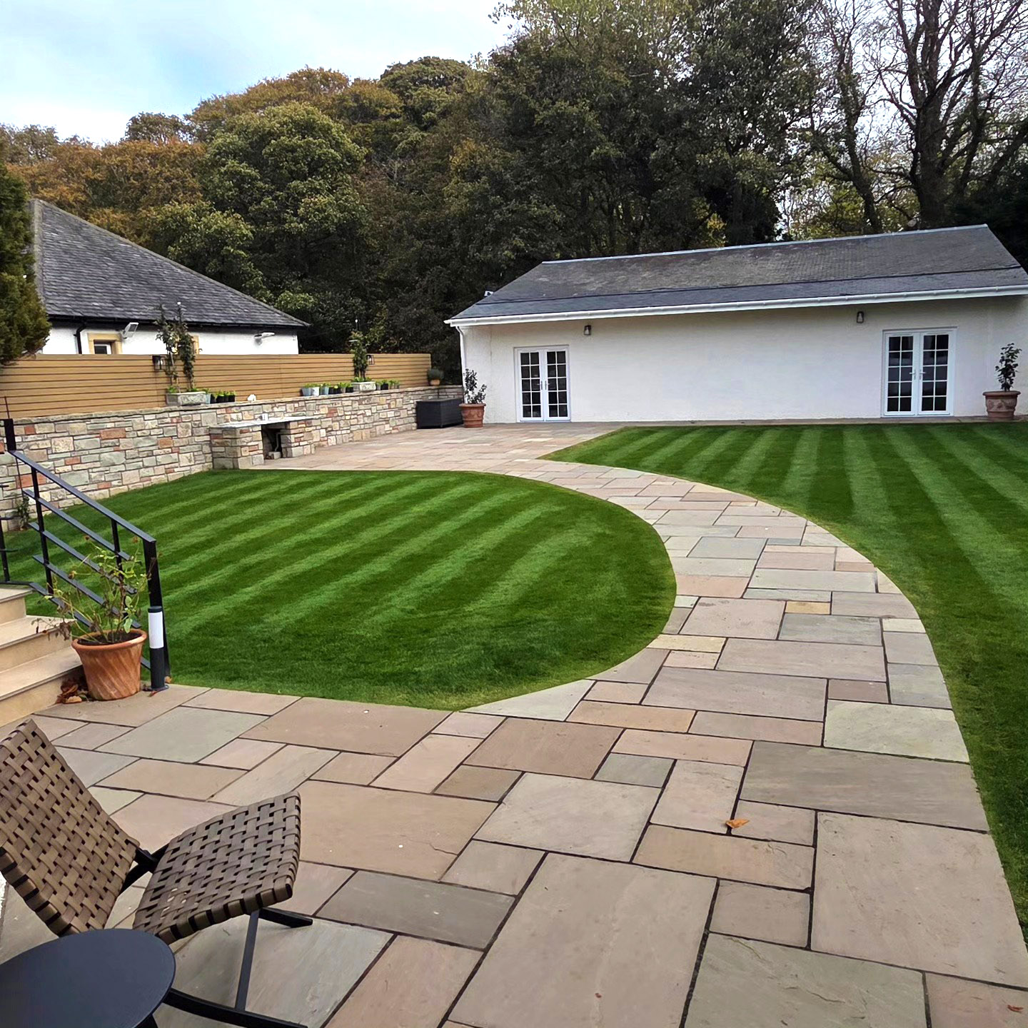Curved sandstone path through a striped lawn